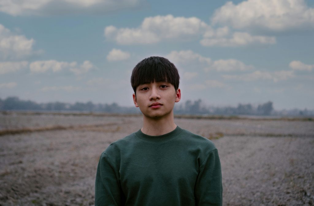 Portrait of a young man outdoors on a cloudy day in nature.