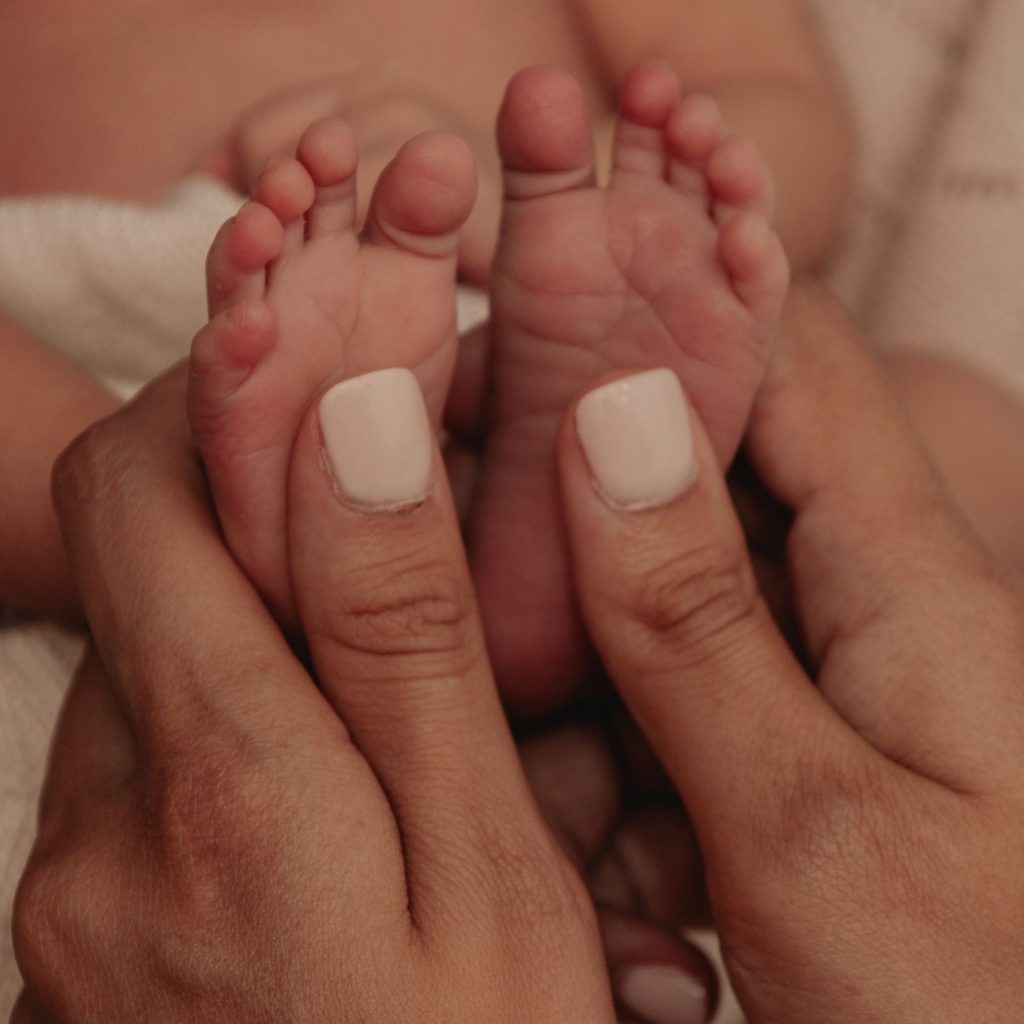Tender close-up shot of mother gently holding her newborn's feet, symbolizing love and care.